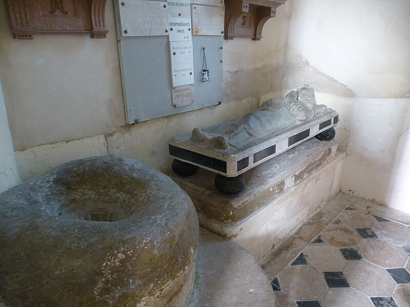 A picture of the tomb and the stone of St. Fiacre. The stone is indented where it looks like someone could sit in it.